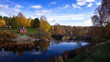 skärgårdsmiljö, vatten, ruska i träden och en liten röd stuga