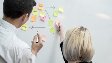 två personer skriver på postit-lappar