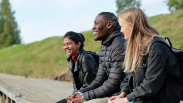 tre studerande sitter vid vattnet