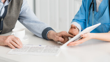 vårdpersonal som visar en äldre person något på en läsplatta