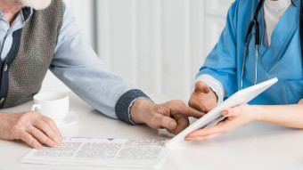 vårdpersonal som visar en äldre person något på en läsplatta