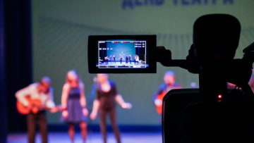 kamera i förgrunden uppträdande på scen i bakgrunden