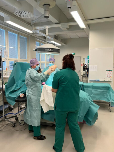 Three people in scrubs preforming a medical procedure