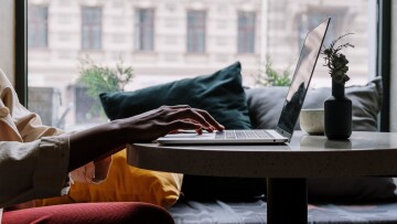 person vid dator, armen och datorn syns i profil