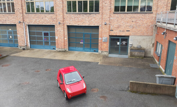 Little red car model Buddt EV in an industrial setting