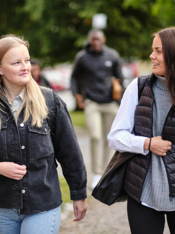 Två studerande promenerar i park